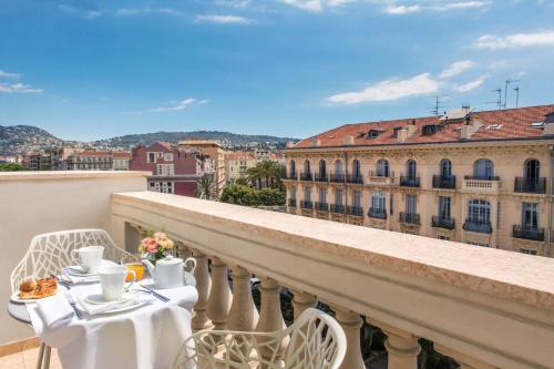 a table and chairs on a balcony with a view at Boscolo Nice Hotel & Spa in Nice