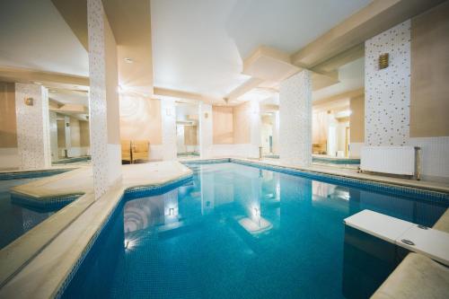 a large swimming pool with blue water in a building at Flagman Hotel in Novovolkovo