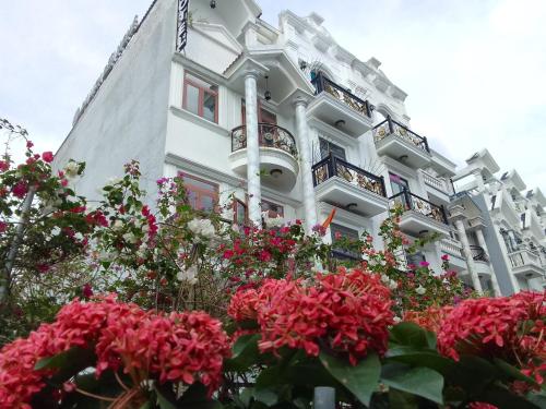 Un bâtiment blanc avec des fleurs devant lui dans l'établissement Amor Hotel, à Hô-Chi-Minh-Ville