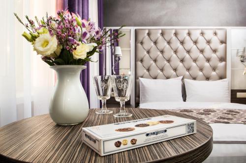a table with a vase of flowers and wine glasses at BonApart Hotel by UHM in Kyiv
