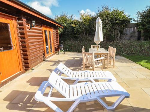 a patio with two chairs and a table and an umbrella at Pine Lodge in Oakham