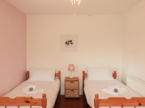 two beds in a room with two tables and a lamp at Sweetheart Cottage in Dalbeattie