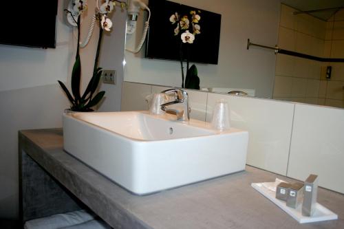 a white sink in a bathroom with a mirror at Hotel Saint Daniel in Péruwelz