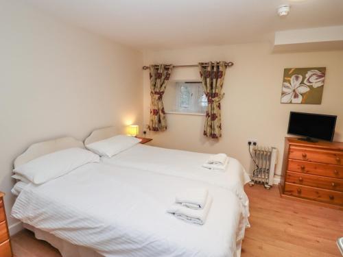 a bedroom with a large white bed and a television at Greyhound Barn in Ampney Crucis