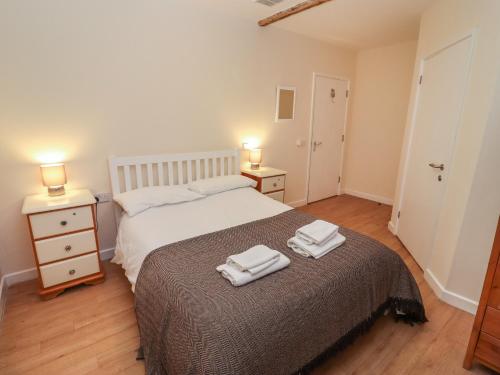 a bedroom with a bed with two towels on it at Greyhound Barn in Ampney Crucis