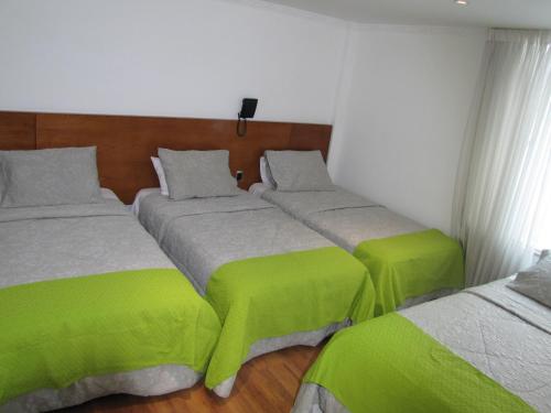 two beds in a room with green and white at Hotel Casa Mahanaim Colferias, Bogotá in Bogotá
