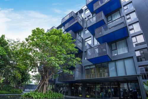 an apartment building with blue balconies and a tree at The Deck patong Luxury Apartments The Deck patong in Patong Beach