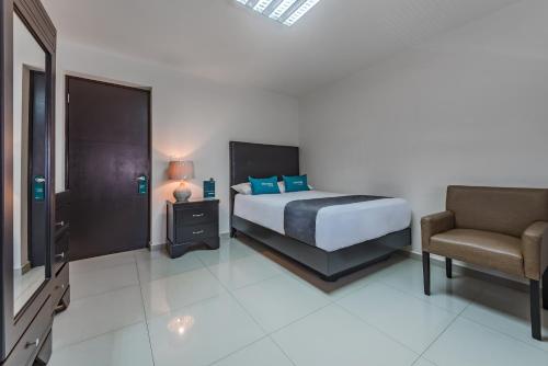 a bedroom with a bed and a chair and a television at Suites Ejecutivas Monterrey in Monterrey