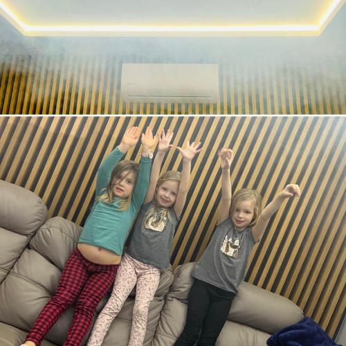 two girls sitting on a couch with their hands in the air at Willa na Mazurach ze SPA, Basenem i Jacuzzi in Giże