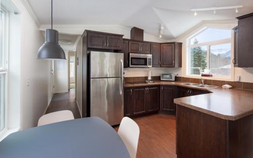 a kitchen with wooden cabinets and a stainless steel refrigerator at Crazy Creek Resort in Malakwa