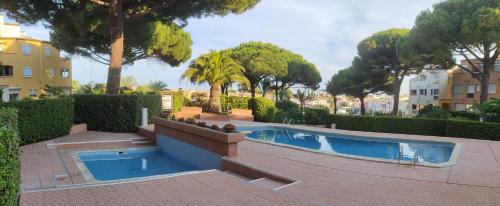 - une piscine dans une cour avec des arbres et des bâtiments dans l'établissement Le Cap Marina, au Cap d'Agde