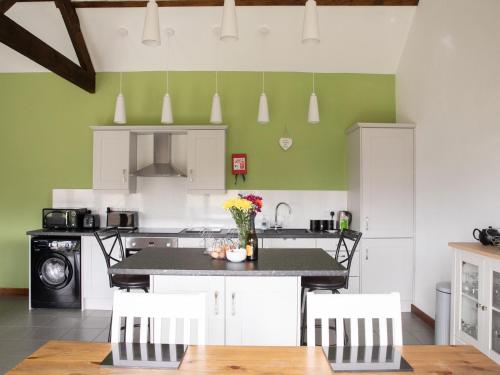 a kitchen with green walls and a table and chairs at 2 Beacon View Barn in Felindre