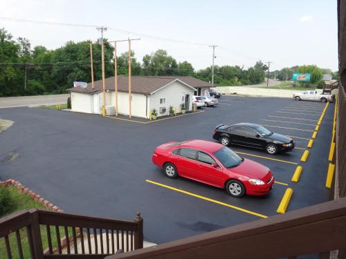 a red car and a black car parked in a parking lot at Indian Mound Motel in Fairmont City
