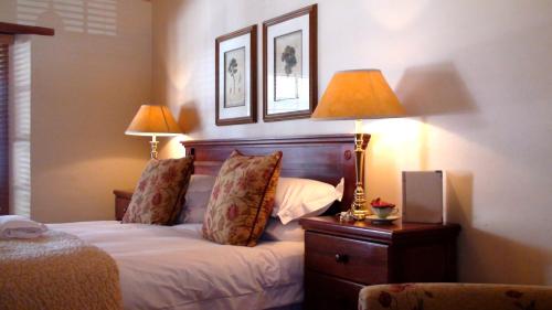 a bedroom with a bed with two lamps on it at De Hoek Manor in Stellenbosch