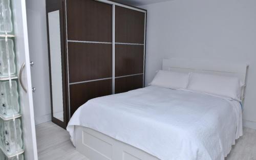 1 dormitorio con cama blanca y cabecero de madera en Departamentos C&G, en Madrid