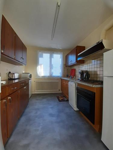 une grande cuisine avec des placards en bois et une fenêtre dans l'établissement Le Nid des Avezous, à Avèze