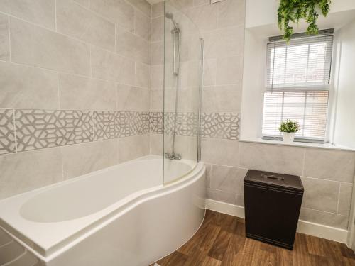 a white bath tub in a bathroom with a window at The Oaks Cottage in Penrith