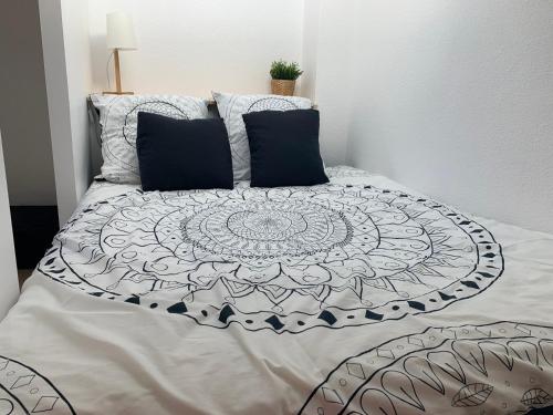 - un lit avec une couette et des oreillers en noir et blanc dans l'établissement Maison vacances résidence privée Piscine Loupian-Mèze, à Loupian