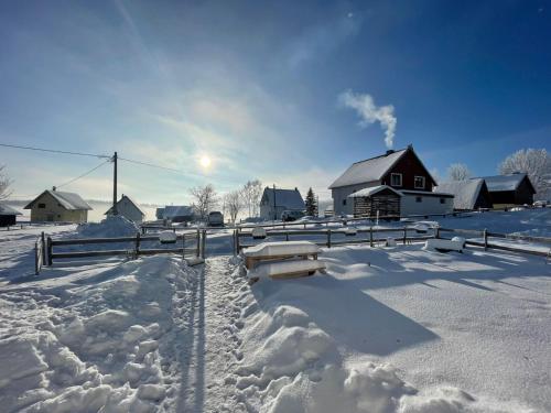 a snow covered village with a house and a barn at Guest House SARA in Žabljak