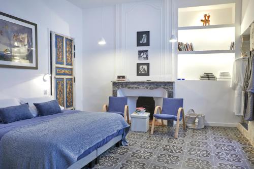 een slaapkamer met een bed en stoelen en een open haard bij Beautiful Art Lovers Apartment in Béziers