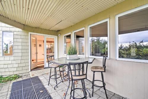 a patio with a table and chairs and windows at Unique Port Ludlow Home with 3 Decks and Hot Tub! in Port Ludlow