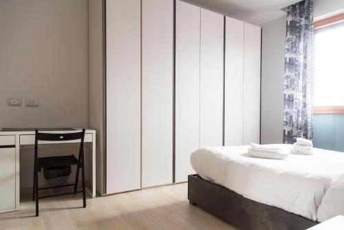 Habitación blanca con cama y escritorio en YouHosty - Inganni 74, en Milán