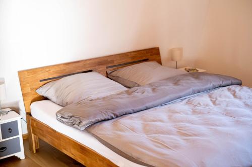 a bed with a wooden headboard and two pillows at Hof Ruemland Ferienwohnungen in Hollingstedt
