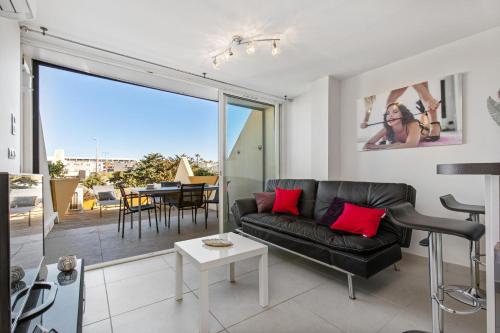 un salon avec un canapé en cuir noir et une table dans l'établissement Village Naturiste R4N - Le Wildly Héliopolis Luxe, au Cap d'Agde