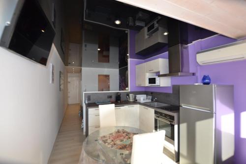 une cuisine avec des murs violets et une table en verre dans l'établissement Studio Naturiste 
