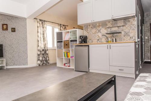Una cocina con gabinetes blancos y una mesa. en Miramar Balchik Apartment 10, en Balchik