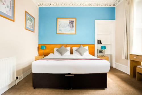 a bedroom with a large bed with a blue wall at Corner Hotel in Carnoustie