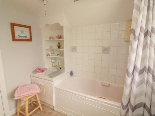 a white bathroom with a tub and a stool at Limestone Cottage in Ennis