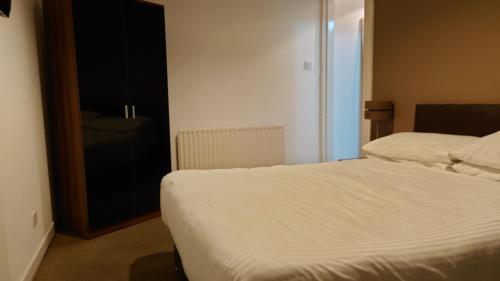 a bedroom with a white bed and a black cabinet at Corner Hotel in Carnoustie