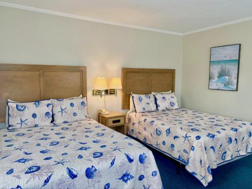 a bedroom with two beds with blue and white sheets at The Heights Hotel in Falmouth