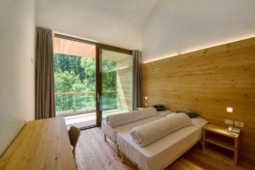a bedroom with a couch and a large window at Vallesinella Hotel Restaurant Bar in Madonna di Campiglio