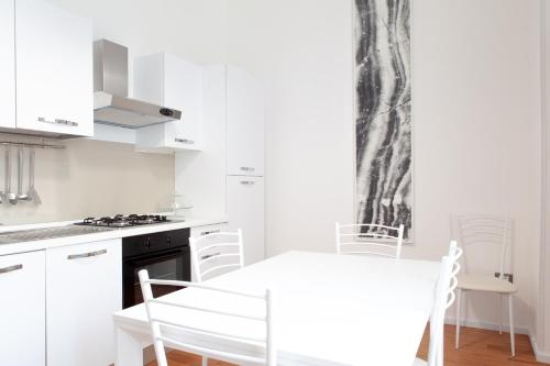 a white kitchen with a white table and chairs at AC Home in Novoli