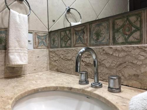 ein Waschbecken mit einem Wasserhahn und einem Handtuch in der Unterkunft Chalé Luxo Frente Piscina - Praia da Pipa in Pipa