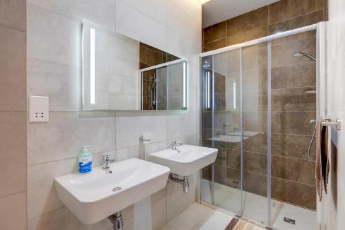La salle de bains blanche est pourvue d'un lavabo et d'une douche. dans l'établissement Deluxe Apartment with Valletta and Harbour Views, à Sliema