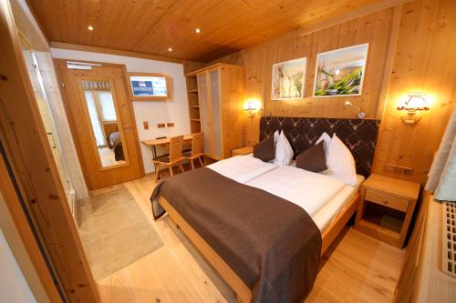 a bedroom with a large bed and a table at TALHEIMER Grias di & Hoamat since 1958 inklusive Therme TAUERN SPA & Jokercard in Saalbach-Hinterglemm