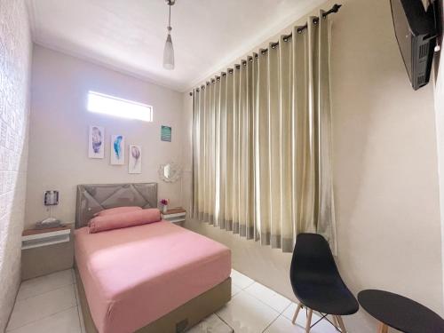 a small bedroom with a pink bed and a chair at The Safa Baiti Guest House Syariah in Rampal