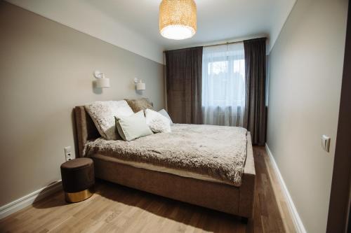 um quarto com uma cama com almofadas e uma janela em Cesis WELCOME apartment em Cēsis