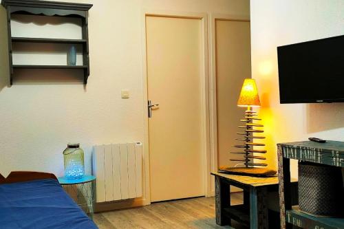 un salon avec un lit et une télévision à écran plat dans l'établissement Maison confortable à Hourtin 45 m² avec piscine partagée sur place !, à Hourtin