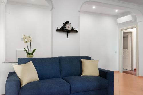 eine blaue Couch in einem Wohnzimmer mit einer Uhr an der Wand in der Unterkunft Il Sogno in Sorrent