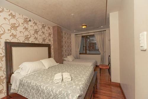 a bedroom with a bed with two white towels on it at Hotel Azul de la Plaza by Chat Noir in Cuenca