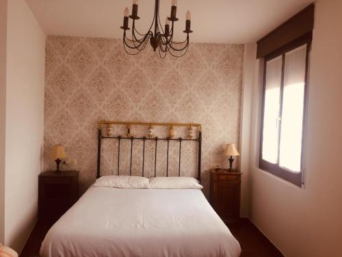 1 dormitorio con cama y lámpara de araña en Casa Vacacional Torredano II, en Nalda