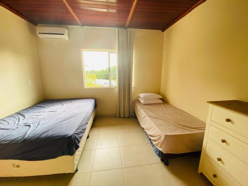 2 camas en una habitación pequeña con ventana en Itacimirim Summer Houses 2/4 Pé na areia, en Camaçari