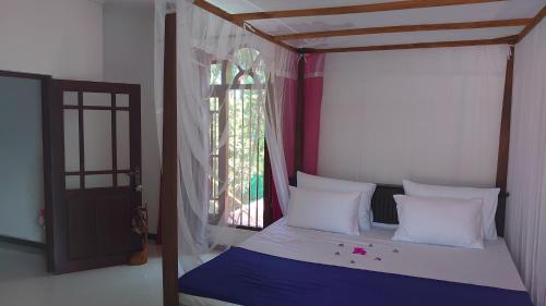 a bedroom with a canopy bed with a window at Isurindi Villa in Midigama East