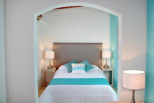 a bedroom with a large white bed with blue pillows at Hotel La Casa de María in Oaxaca City