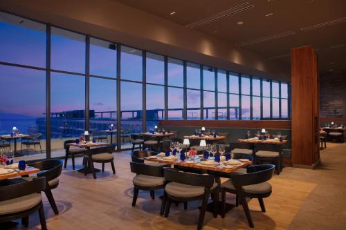 a restaurant with tables and chairs and large windows at Secrets Bahia Mita Surf and Spa - All Inclusive - Adults Only in Punta Mita