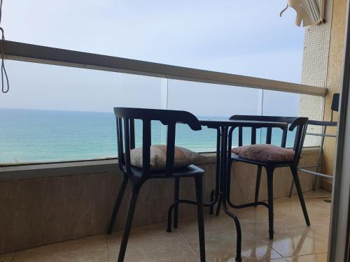 two chairs and a table in front of a window at Sea View Deluxe in Bat Yam